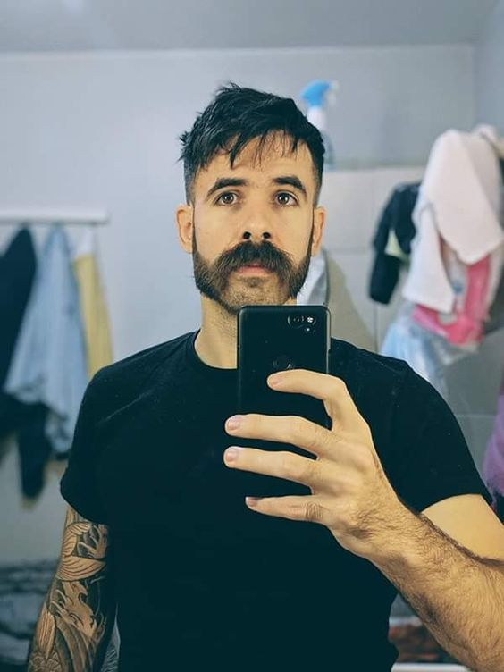 Gunslinger beard mustache style man taking mirror selfie