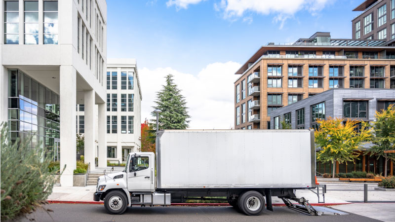 A moving truck rental is parked in front of an apartment complex. 