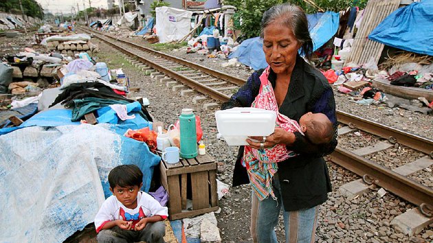 Sumarni (73) bersama dua cucunya menyantap makanan seusai pulang dari kebaktian Natal di pinggir rel kereta api di kawasan Tanah Tinggi, Kecamatan Johar Baru, Jakarta Pusat, yang digelar pada Kamis (17/12), lebih cepat sepekan dari libur Natal.