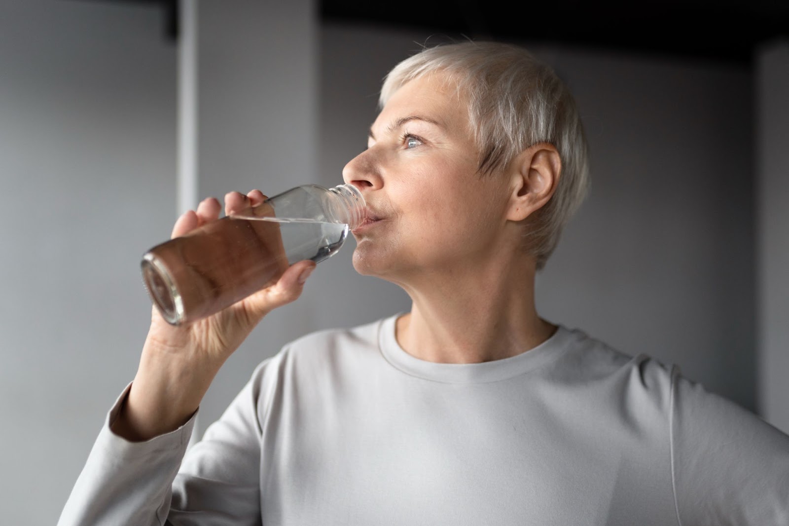 Mulher bebendo água em garrafa plástica