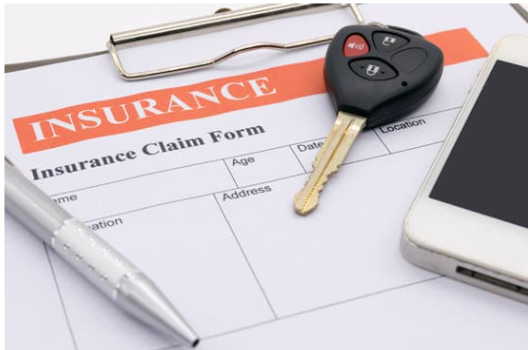 insurance claim form with a key and phone on top 
