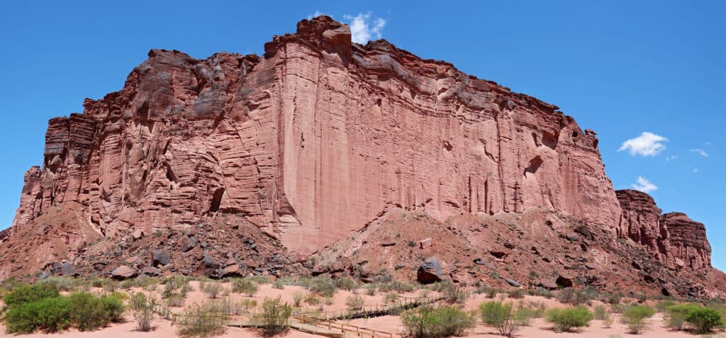 A low angle shot of a deeply red and very high rocky wall  in Talampaya National Park, Argentina