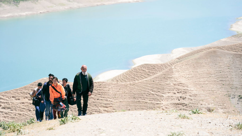 A screen still from To the Ends of the Earth, featuring Yoko, played by Atsuko Maeda, walking up dunes of sand with her crew and their guide in Uzbekistan.