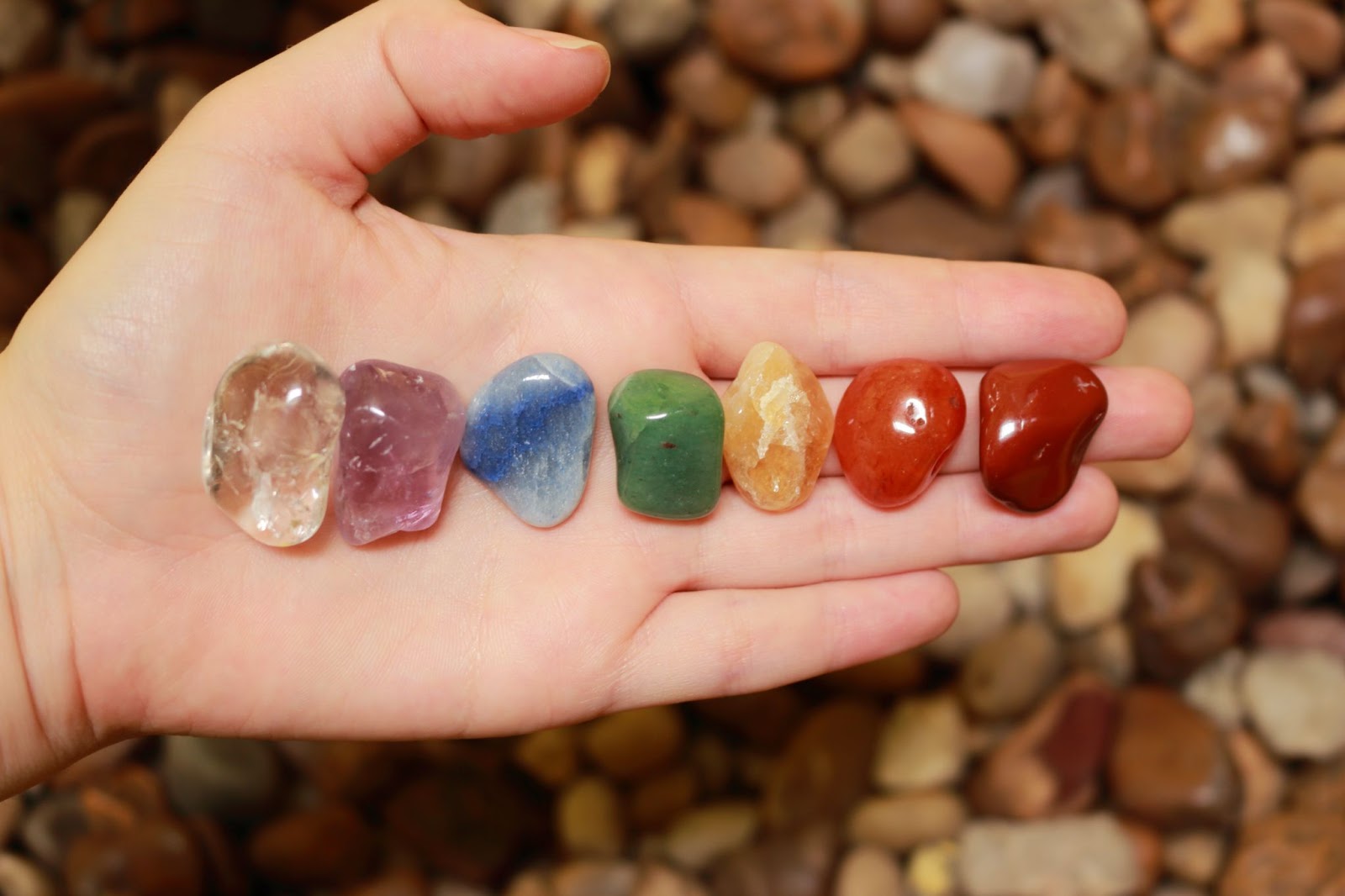 A row of rainbow coloured crystals in an open palm. 