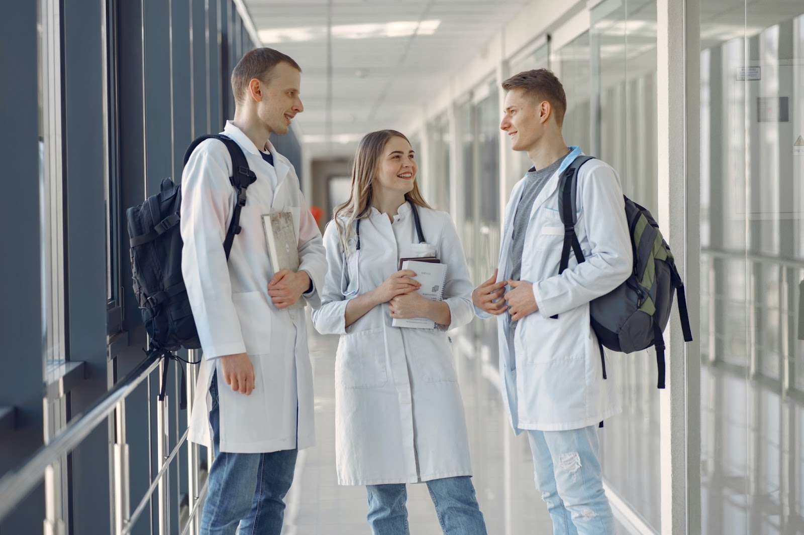 Group of three medical students talking to each other in a hallway