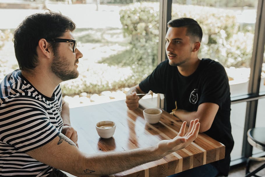 Two men have a conversation at a table