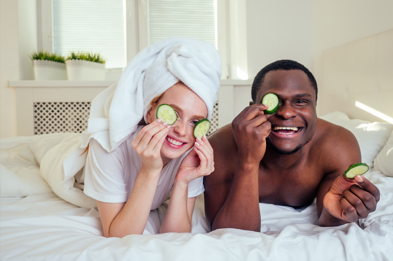 man and woman holding cucumbers up to their eyes