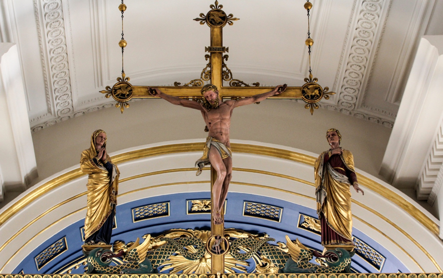 Imagem de grande crucifixo na parte alta do interior de uma igreja