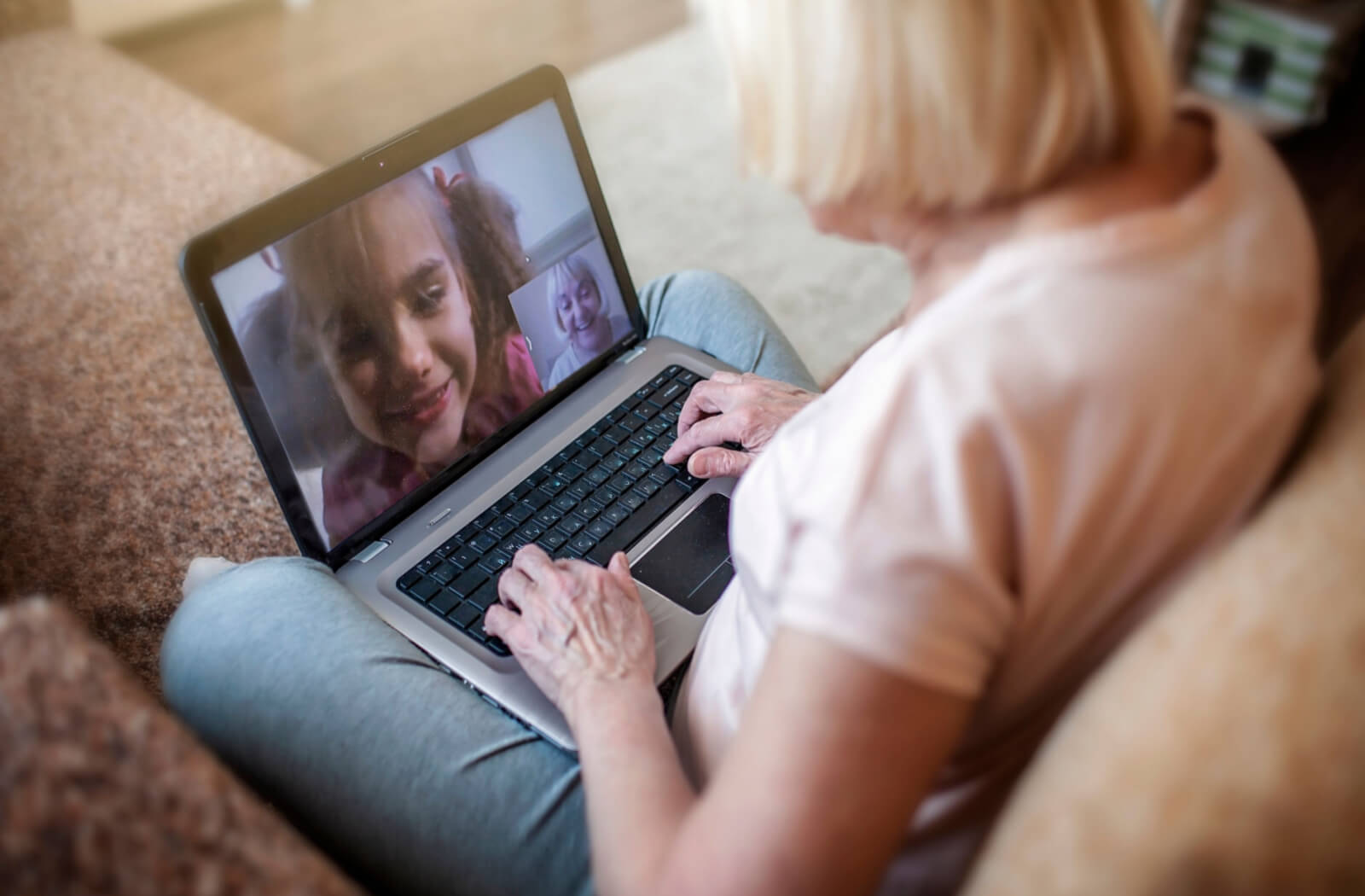 a senior woman video chats with her granddaughter over a laptop