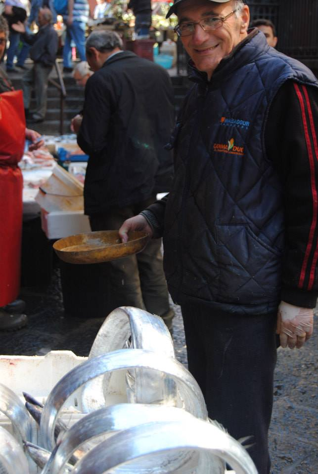 A fishmonger smiles behind his long silver fish coiled up into circles at the Catania Fish Market.