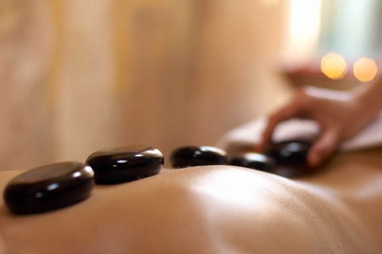 Back massage with traditional dried leaf medicine, coconut oil, hot stones.