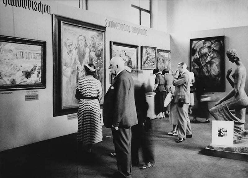Photograph of Degenerate Art Exhibition in Munich, 1937. Pictured are Lovis Corinth’s Ecce Homo (2nd from left), Franz Marc’s Tower of the Blue Horses (wall at right), next to Wilhelm Lehmbruck’s sculpture Kneeling Woman.