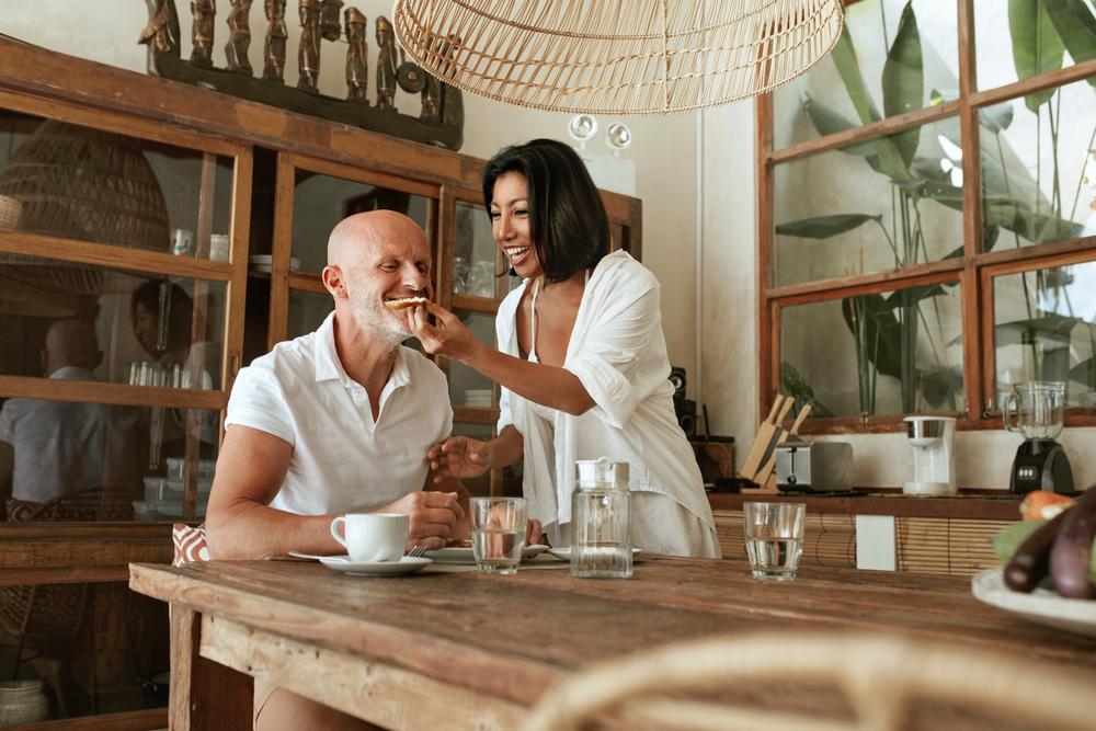 Middle-aged couple enjoying food at kitchen table.