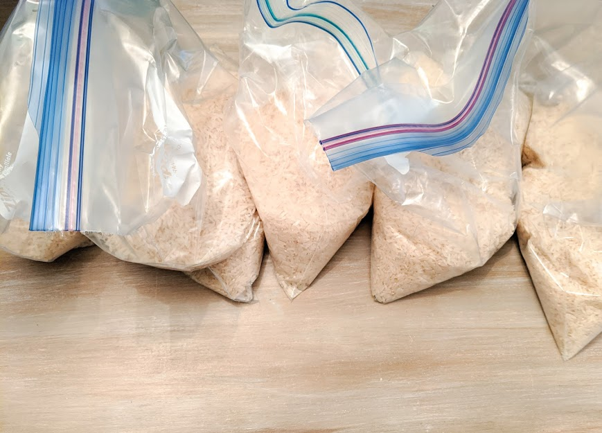 White long grain rice in 5 separate gallon plastic Ziploc bags.