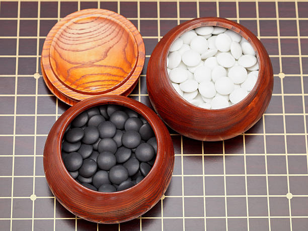 Black and white stones in wooden bowls on a go weiqi board - How to Play Go Game or Weiqi for Beginners - The Gamerian Gaming Blog