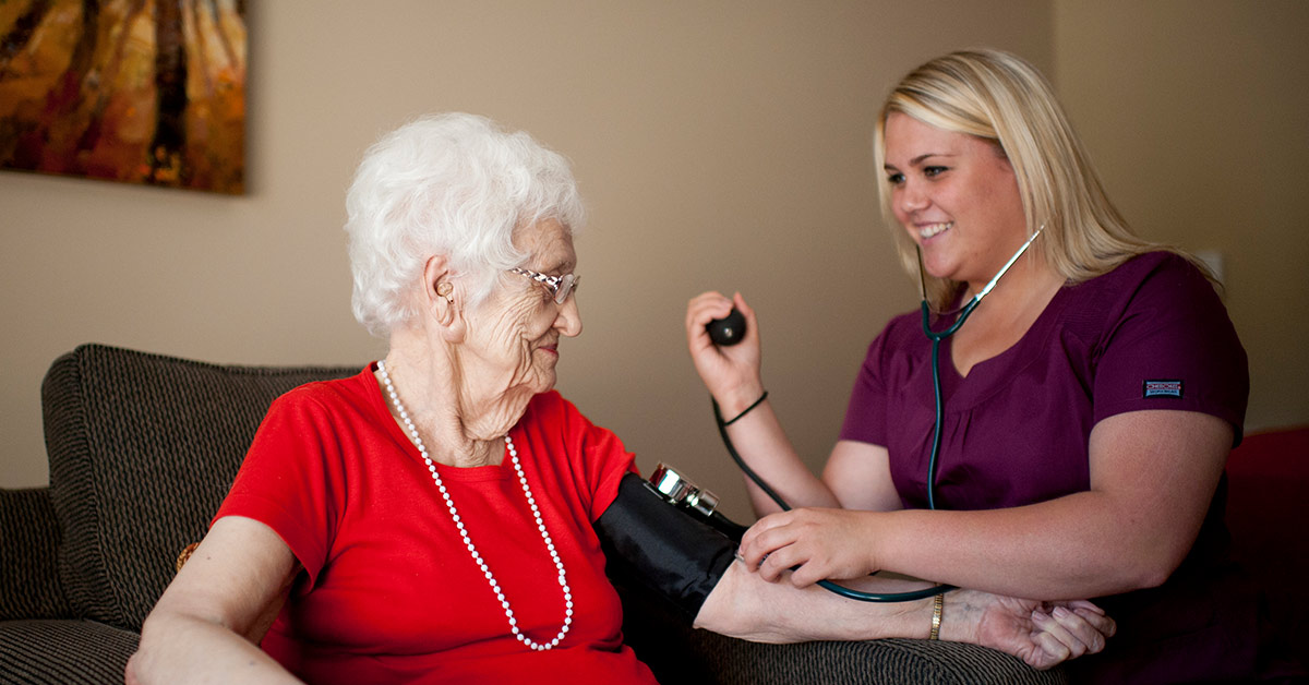 Nurse taking senior woman's blood pressure