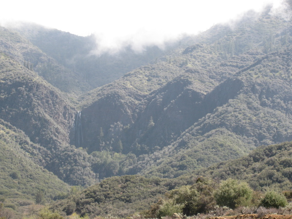 A massive cliff over which a bunch of water is falling.  Clouds are falling over the top of the ridge above.