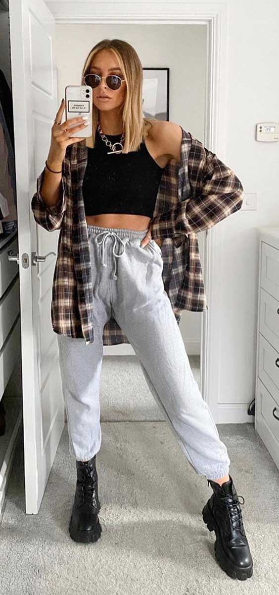 mulher usando um calca jogger cinza com um cropped preto combinado com um casaco xadrez