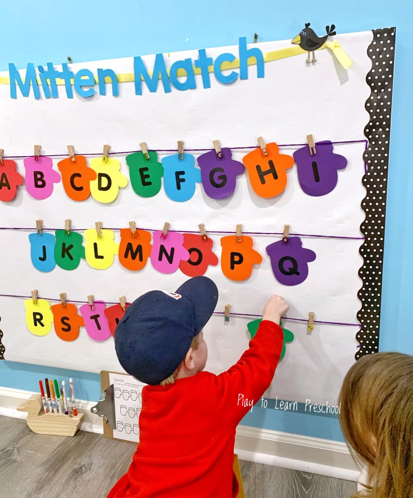  a boy arranging letters written on colored mitten-like papers