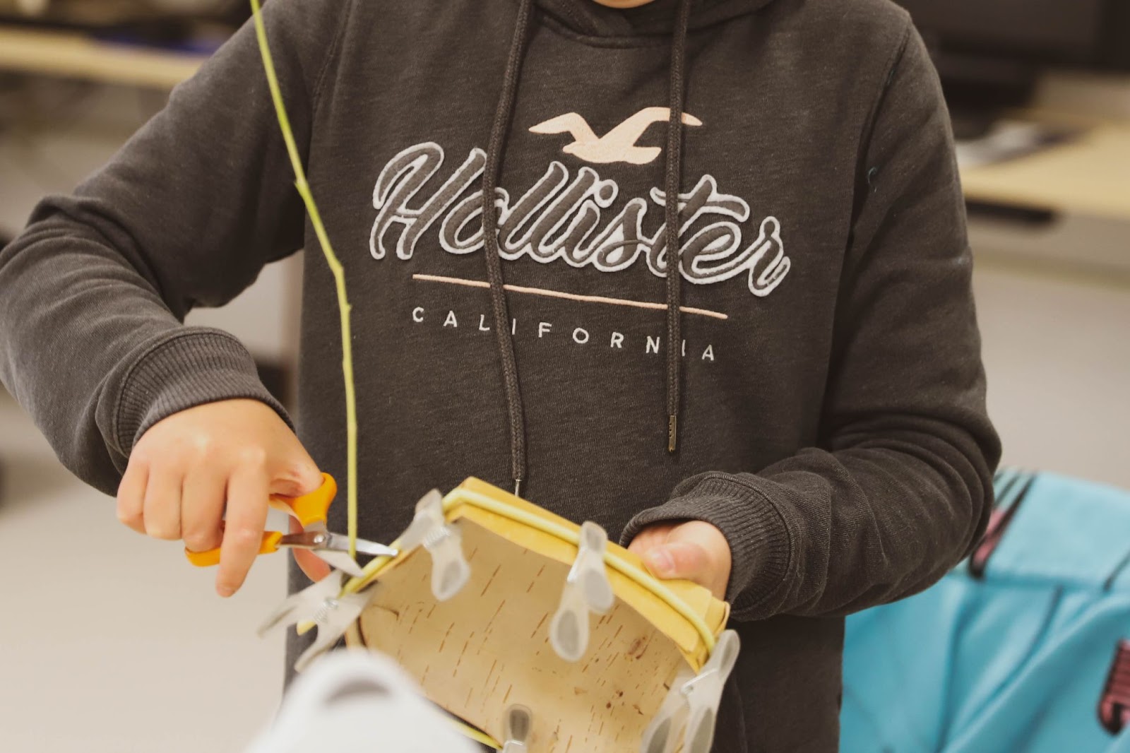 A woman trims the excess willow off of a birch basket