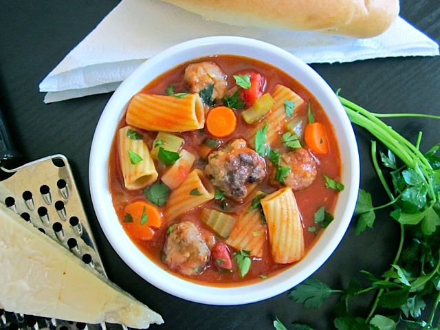 Hearty Meatball Soup in white bowl with grater garnishes on side 