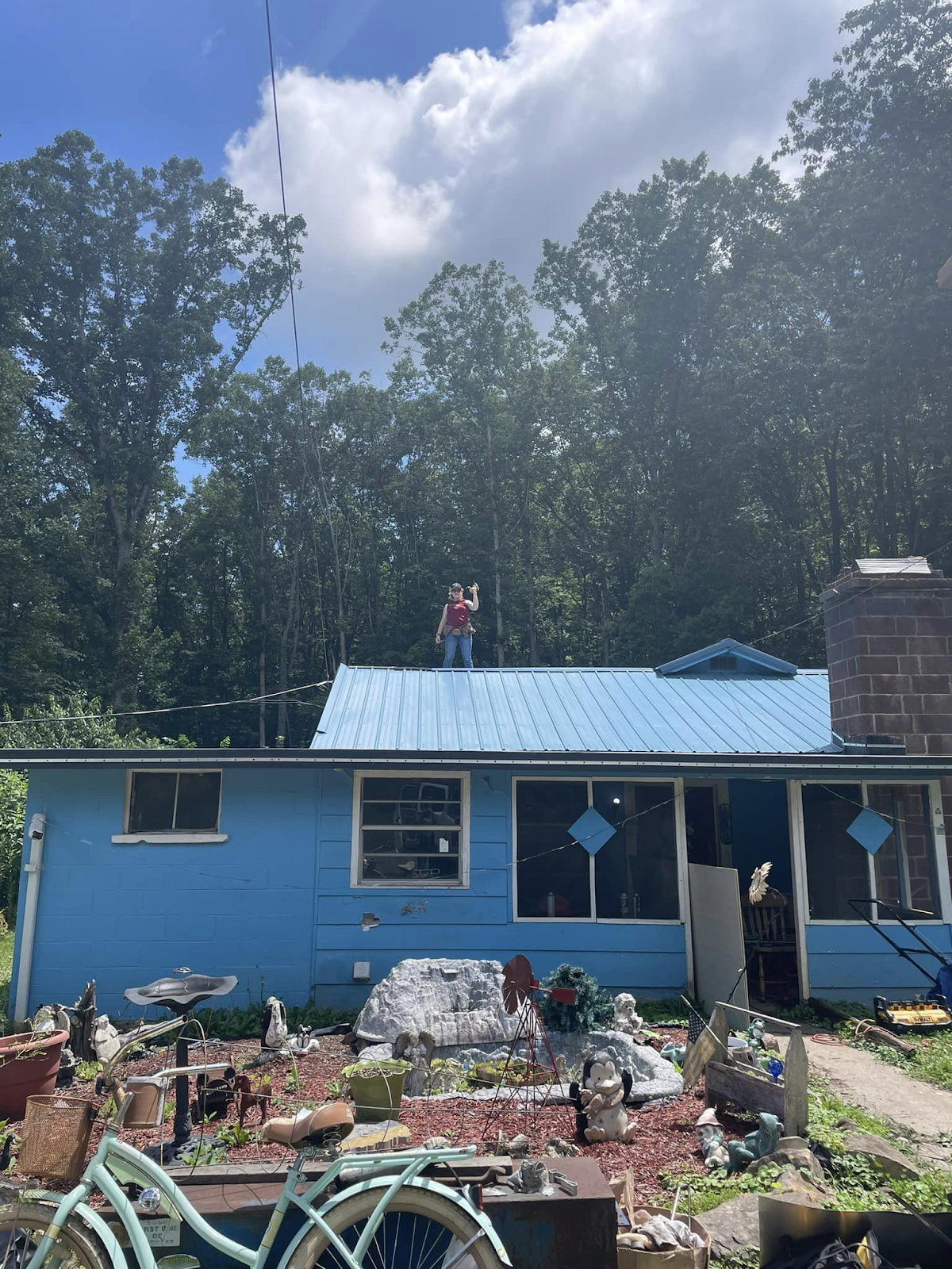 Morgan Pettlon standing on the roof of a blue house