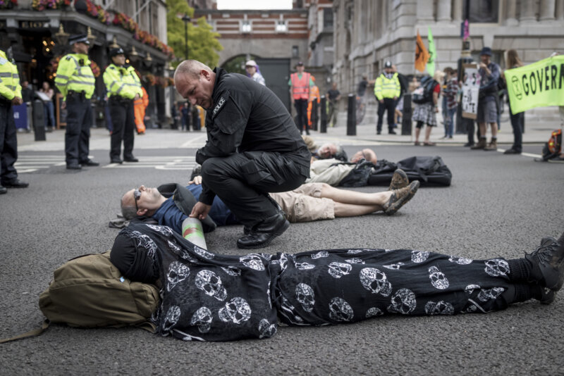 Rebels lying in the middle of a road with a police officer talking to them