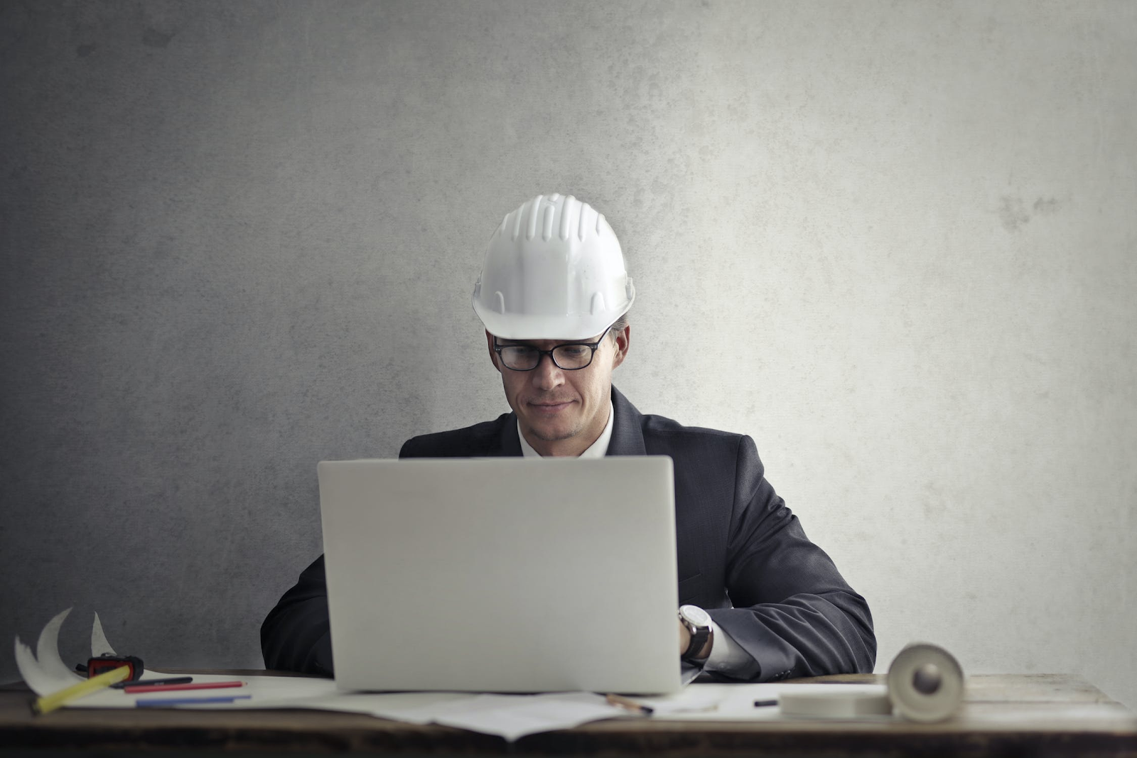 Man with white hard hat working on a laptop