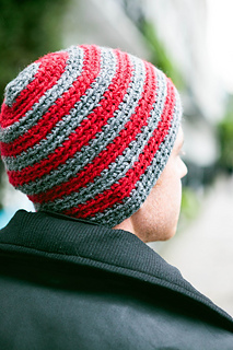 man wearing a red and gray striped crochet beanie