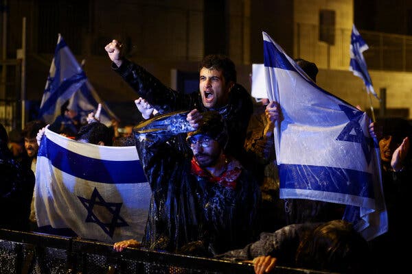 Двоє демонстрантів уночі з ізраїльськими прапорами.