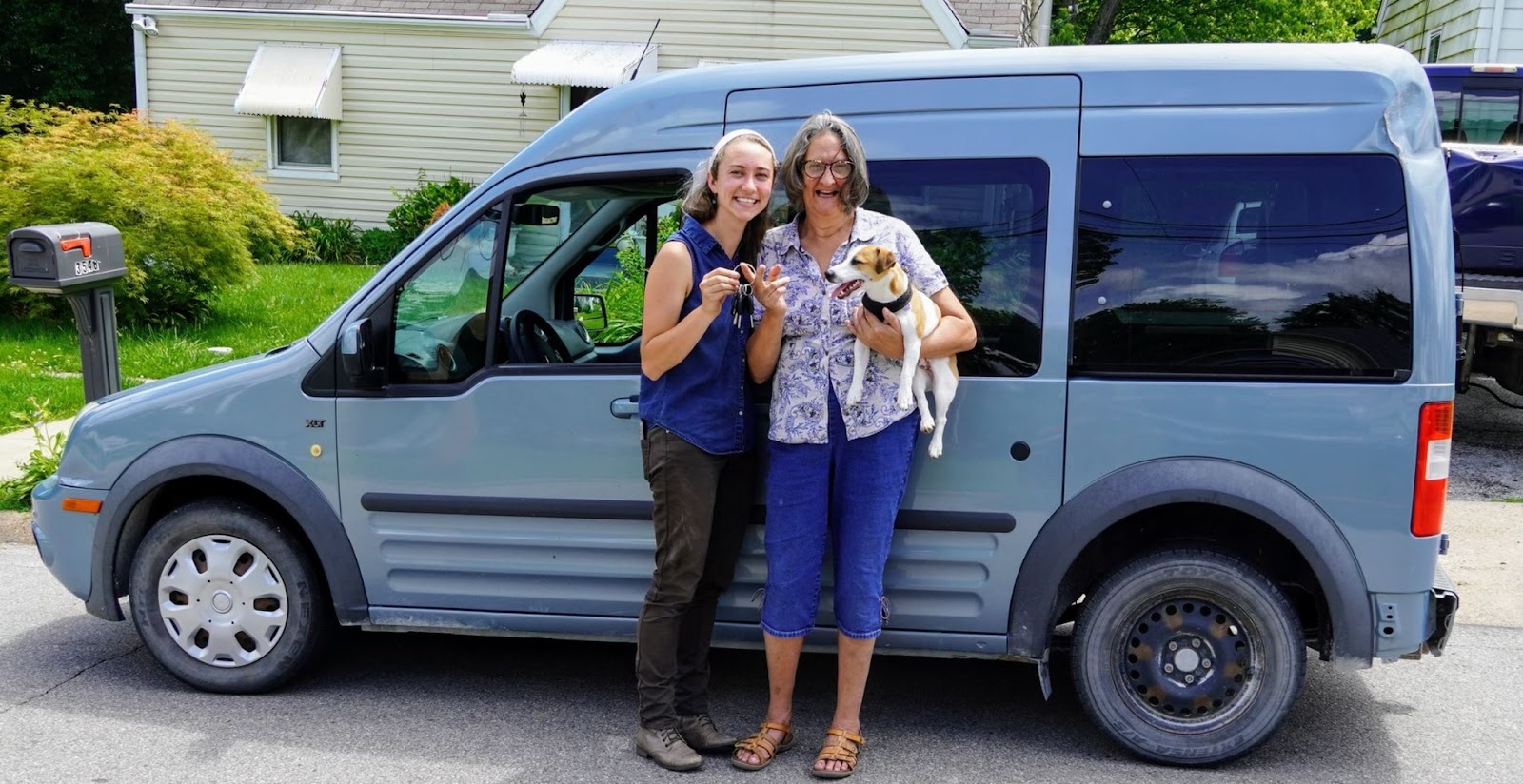 Huemer stands in front of the van next to Mutchler with her dog