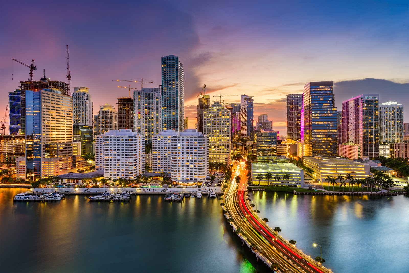 Skyline of Miami at night. It displays many high rise buildings and traffic.