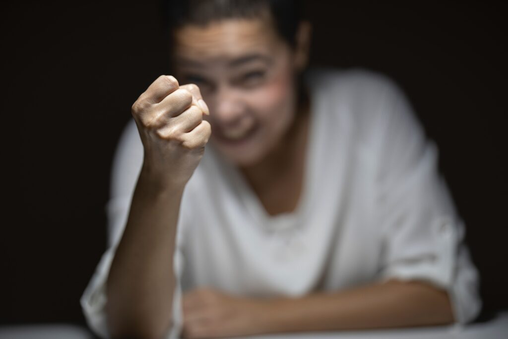 ablurry photo of a woman and her fist is clenched, demonstrating a Highly Sensitive Person's response to pen clicking