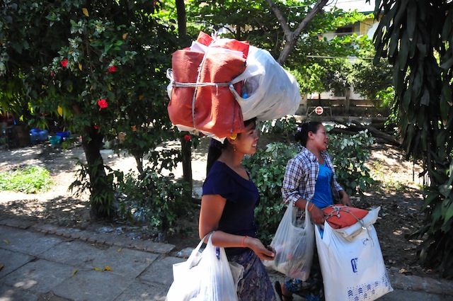 Women walk with heavy loads after disembarking from a train. Thousands still rely on the dilapidated public transport system, with its century-old trains and belching buses, because they cannot afford anything else. Credit: Amantha Perera/IPS