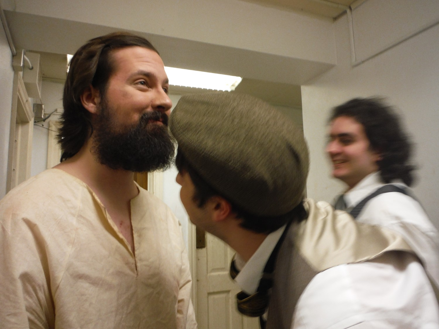 One student in costume for a theater performance examines another student's makeup. 