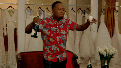 A gif of Winston from New Girl dancing with a champagne glass and bottle in his hands.