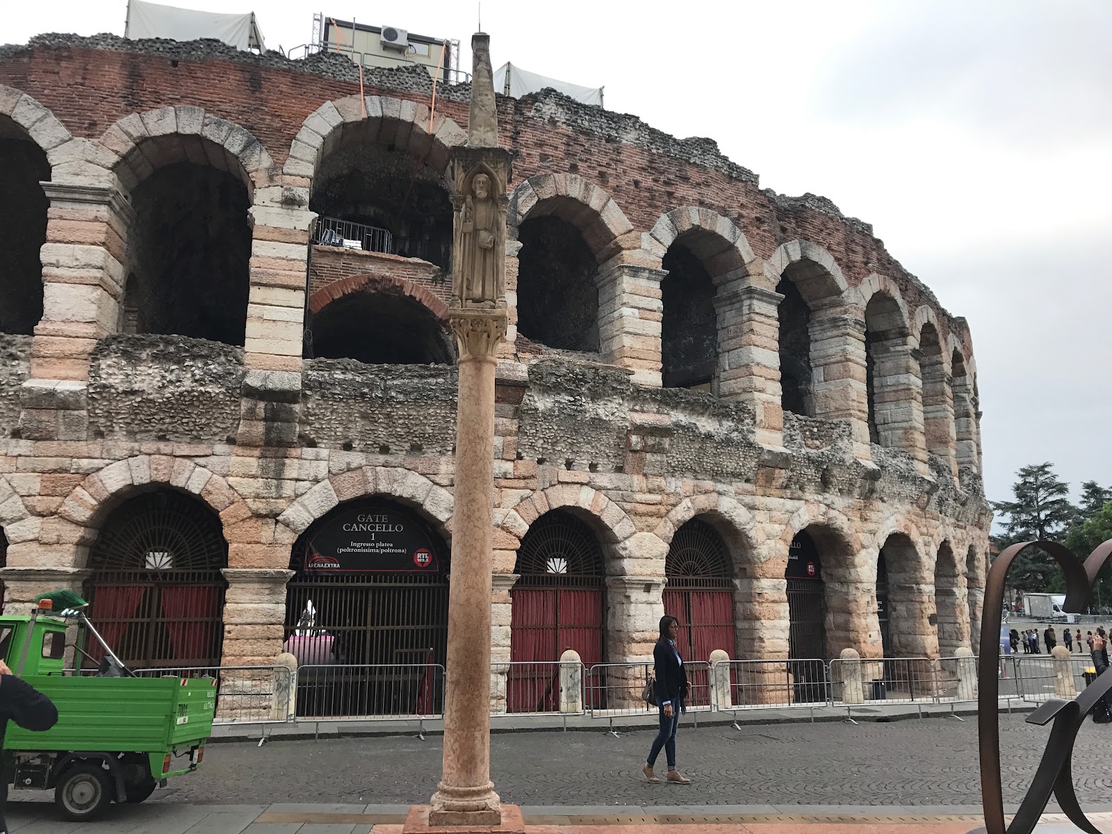 arena di verona, large colosseum is the main attraction in verona, italy. Seen on a cloudy day, tourists in the distance and old column in front of the arena. Be sure to see it on an Italy road trip