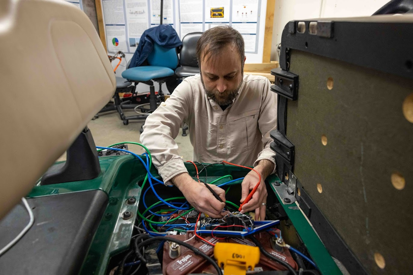 Bobby working on colorful electronic wires under the seat of the golf cart