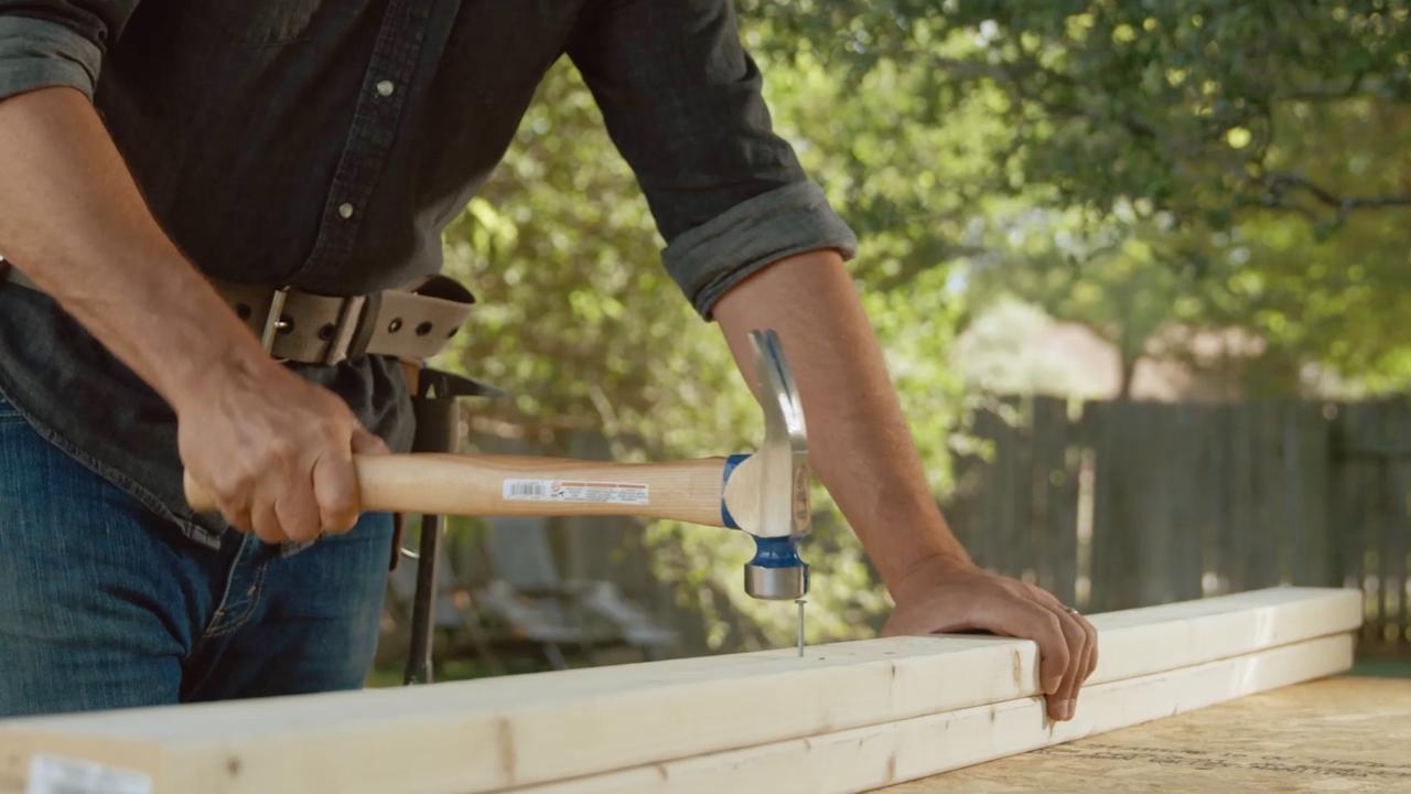 Person holding hammer over a nail