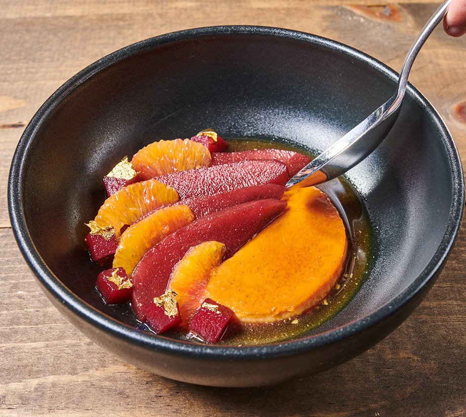 A bowl of colorful food, patterned with a deep red and a bright orange in a sauce.