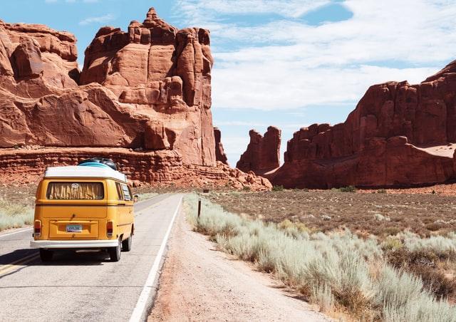 A yellow van on a road in front of a red rock formation

Description automatically generated with low confidence
