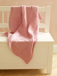 pink loom knit small blanket lying on bench