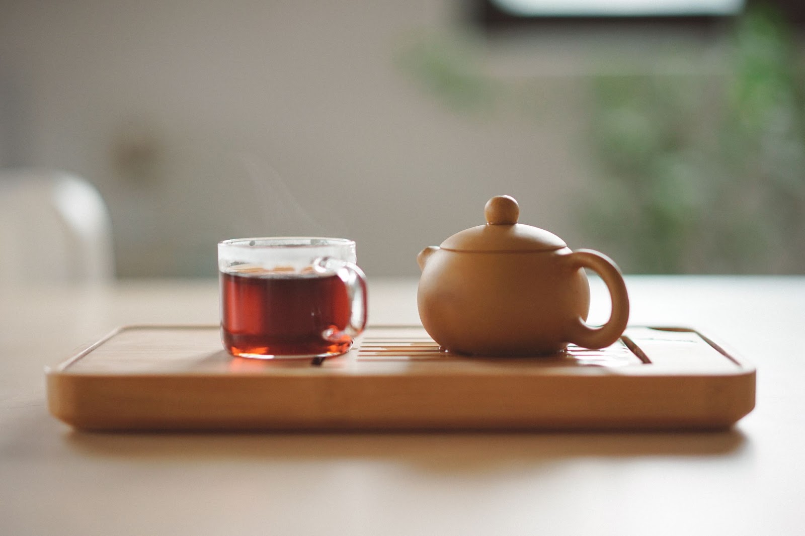  A cup of tea sitting next to a small kettle.