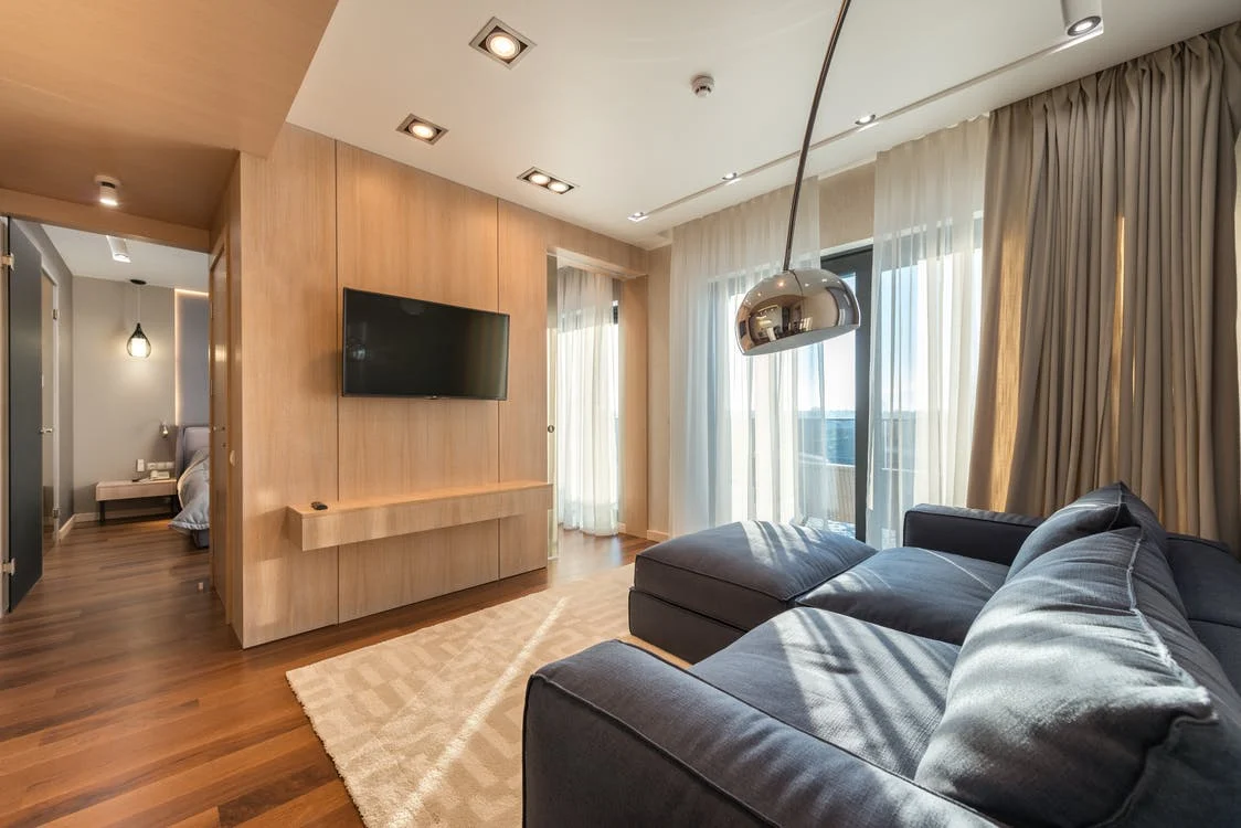 Incidência solar: sala com sofá azul e televisão recebendo luz do sol da janela