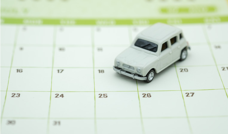 A calendar with a small, white toy car placed on top of it