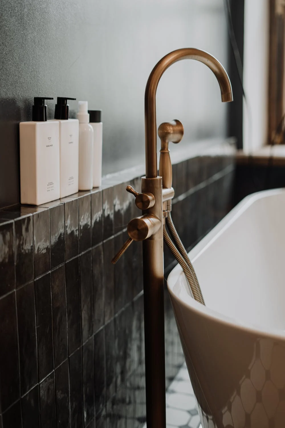 High gloss black tiles behind freestanding bathtub; tile trends 2022; MGSD