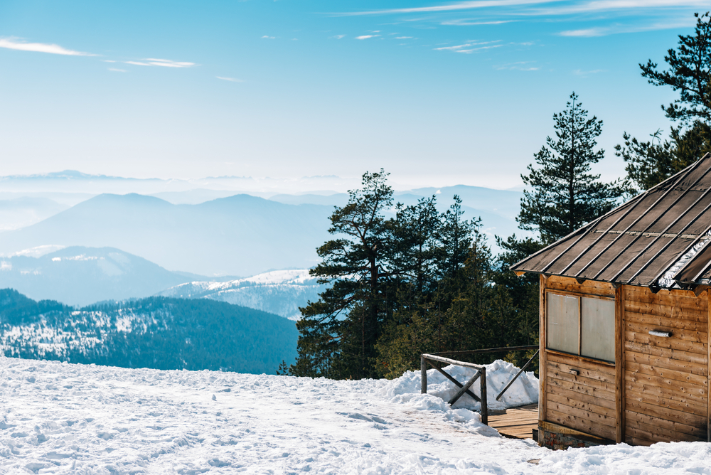 Cabin at top of snowy mountain with a view.