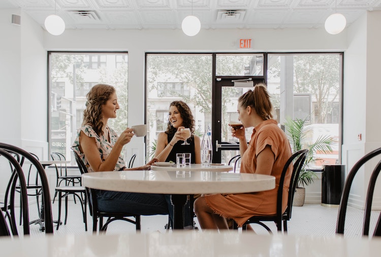 Tre kvinder der drikker kaffe rundt om et bord