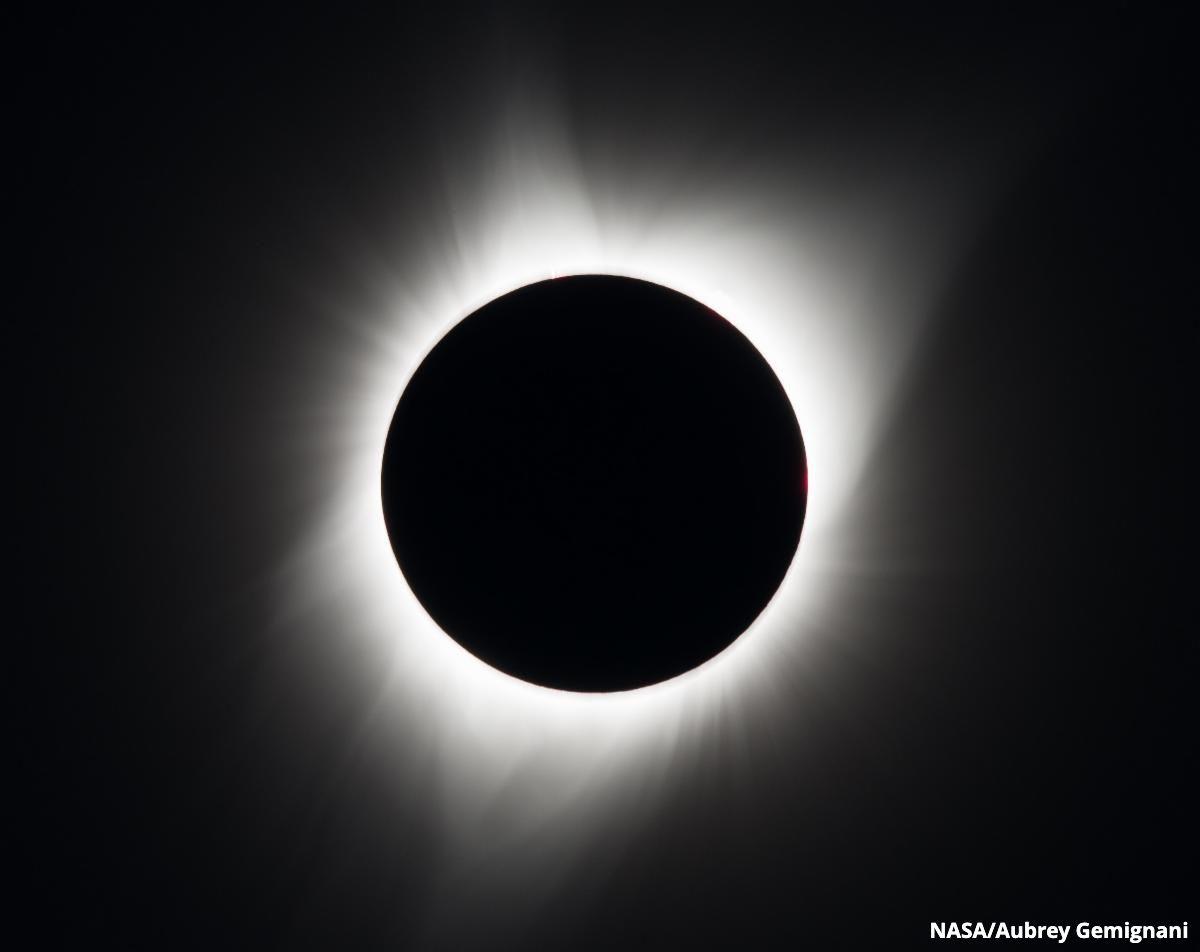 NASA_Aubrey Gemignani image showing a total solar eclipse, a ring of white light radiating away from a black circle.