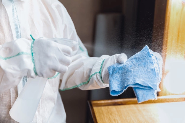A person with gloves is spraying on a cloth. 